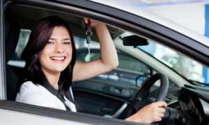 Image of lady smiling with car keys in her used car she has bought.